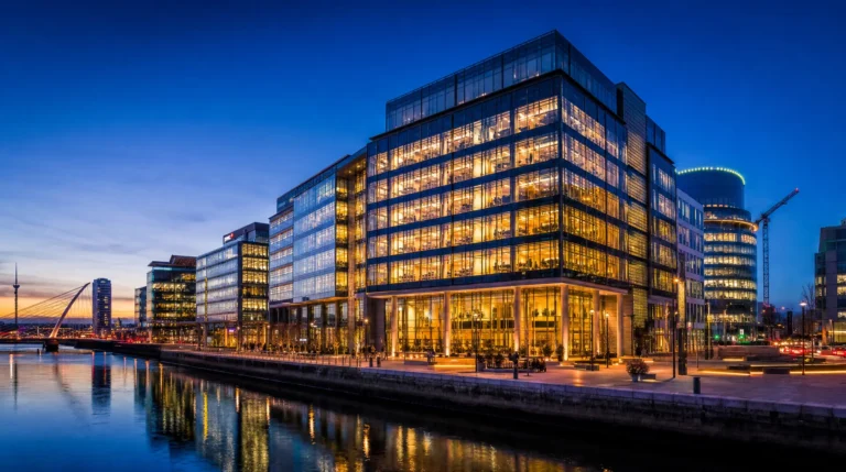 Illuminated glass office complex by a canal at dusk, signaling corporate compliance readiness for global expansion planning.
